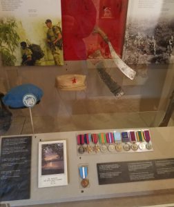 A display in the Welsh Fuseliers museum, showing a Parang, some medals and some hats.